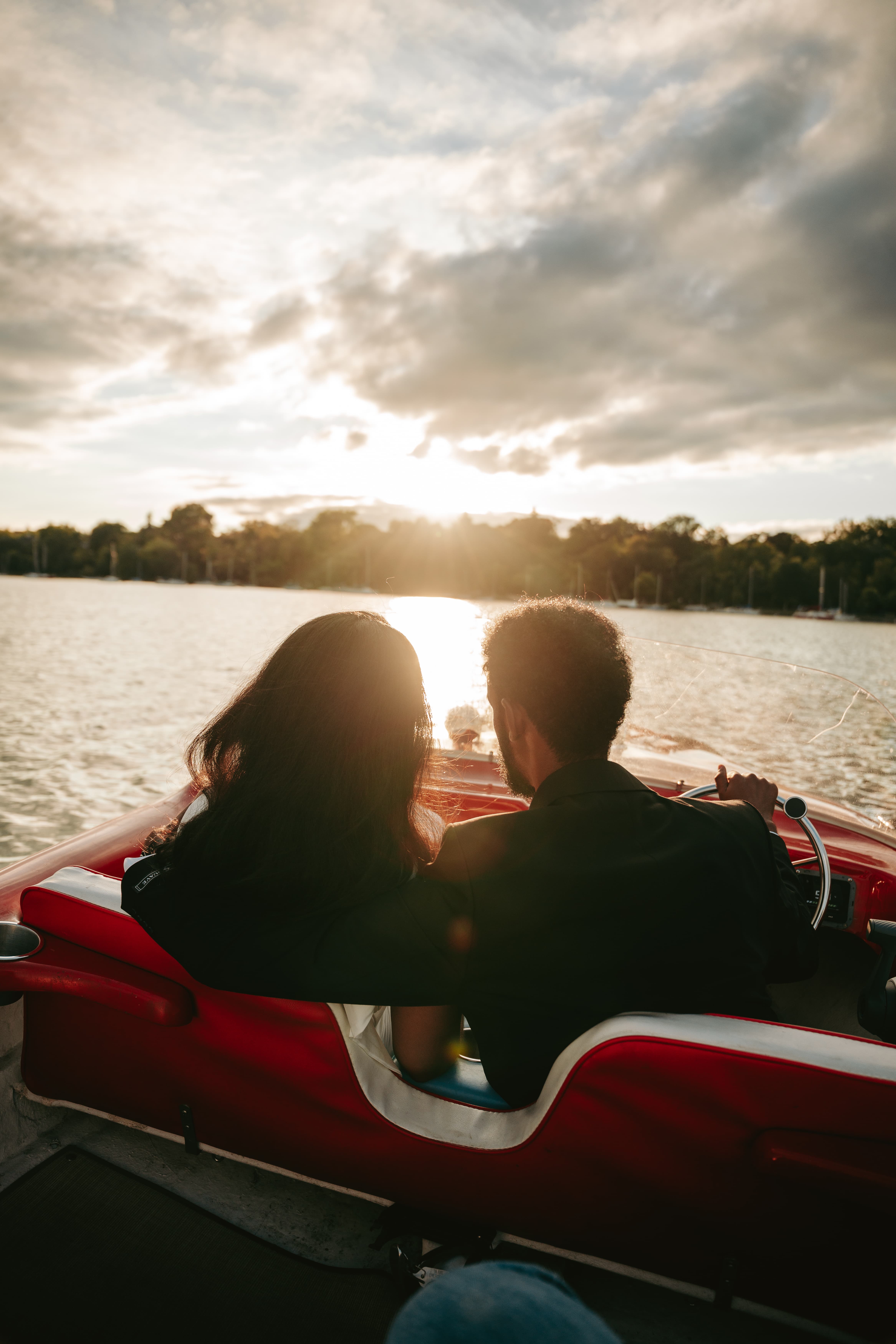 Couple seated in a vintage red boat watching the sunset over the water, romantic couples portrait session